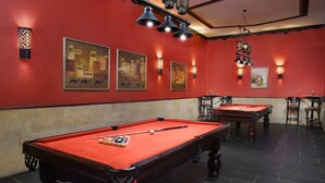 Una mesa de billar con superficie de fieltro rojo, rodeada de baldosas negras.