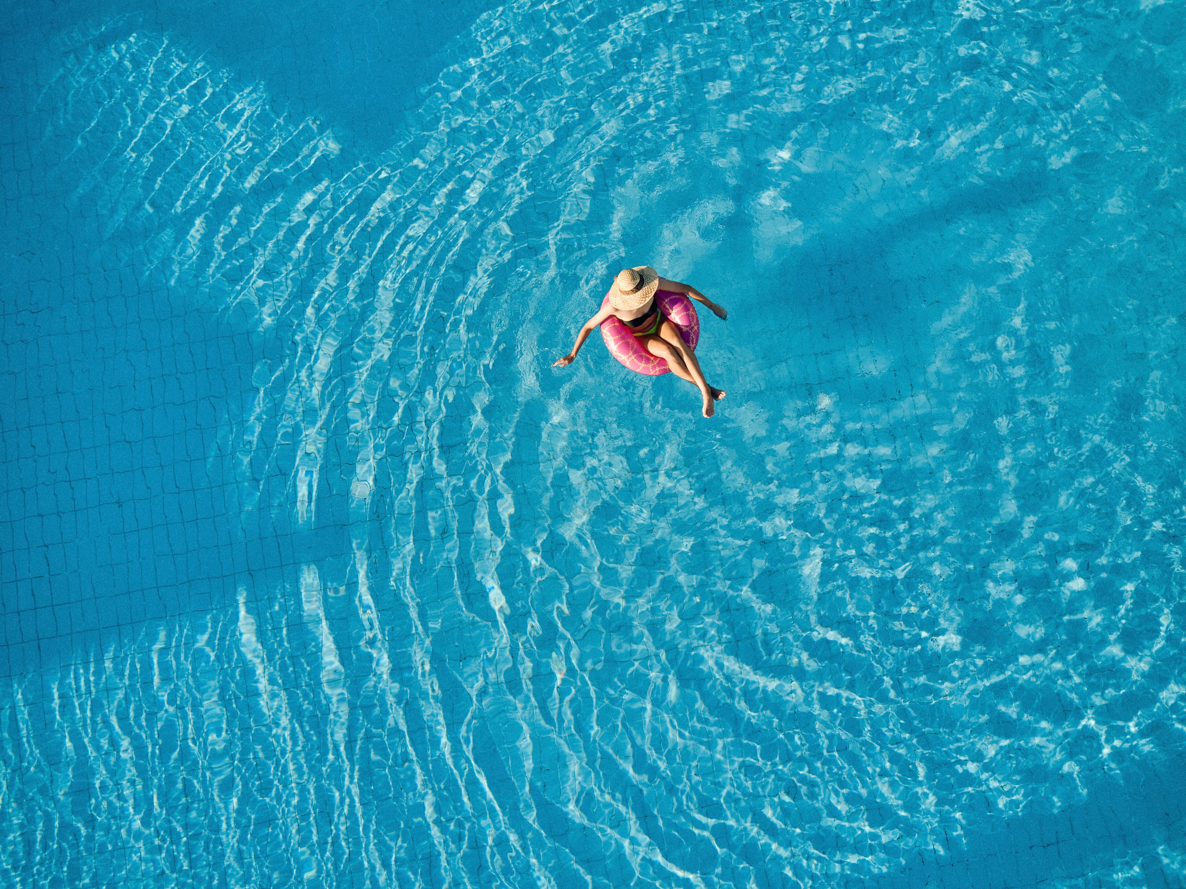 Una persona flotando en una piscina de agua azul cristalina.