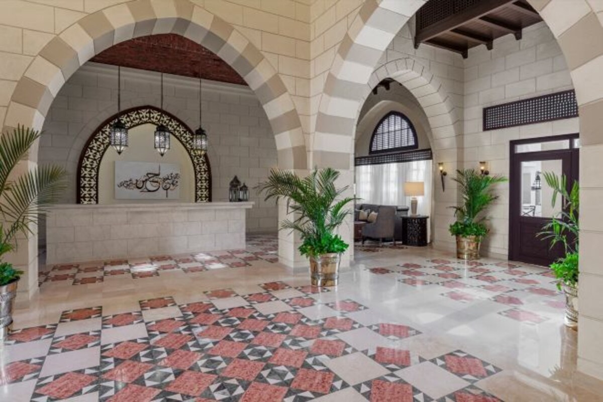 A lobby with arched ceilings, a reception desk, and potted plants.