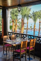An outdoor dining area with a view of palm trees and a pool.