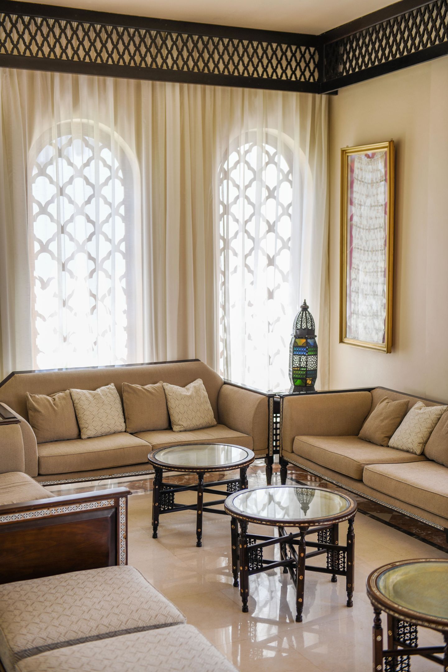A living room with a sofa, two glass-top coffee tables, and a decorative lantern.
