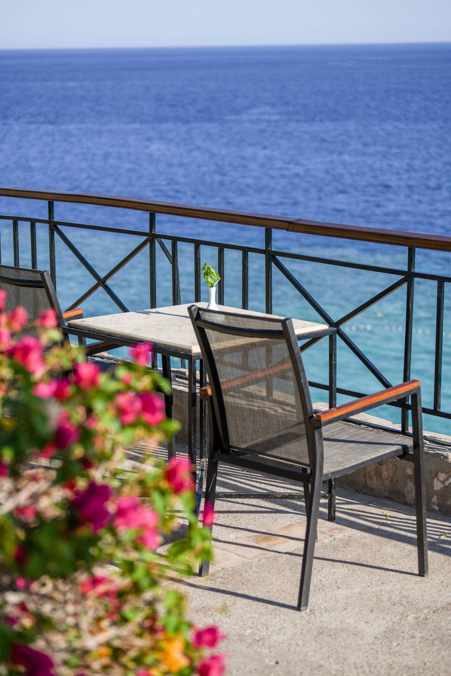 An outdoor seating area with a table and chairs, overlooking the sea.