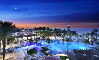 A resort with a swimming pool, palm trees, and a lighthouse.