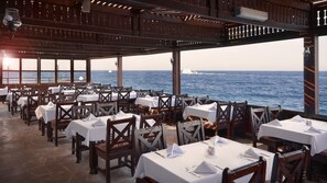 A restaurant with tables set for dining, overlooking the sea.