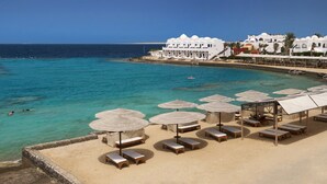 Une plage avec une eau turquoise et limpide, des chaises longues et des parasols.