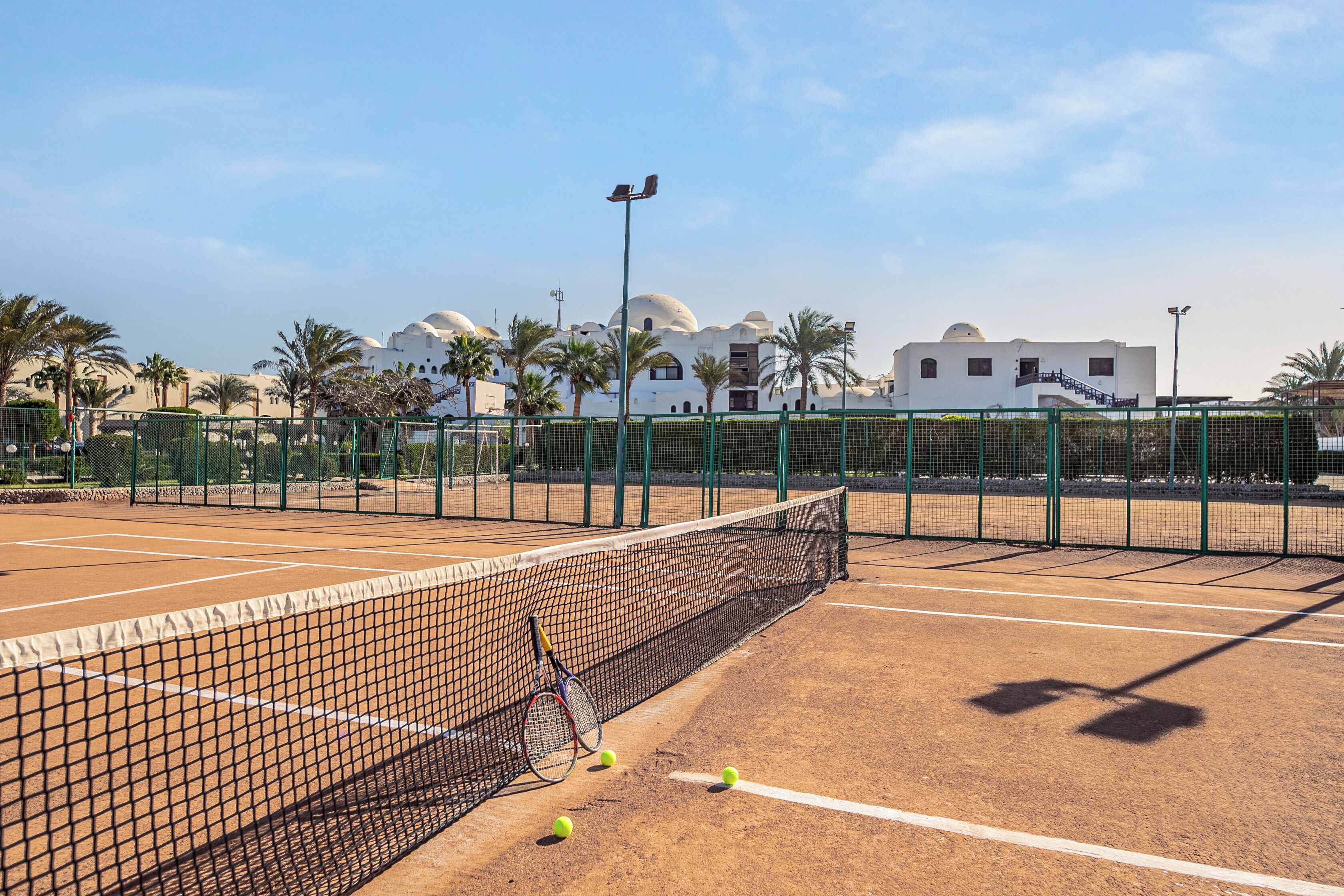 Una cancha de tenis con red, raquetas y pelotas.