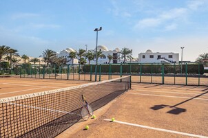 Una cancha de tenis con red, raquetas y pelotas.
