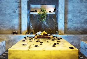 A spa area with a marble reception desk, a wall-mounted shelf with decorative items, and a hanging plant. - Solymar Makadi Sun - All inclusive (Makadi Bay)
