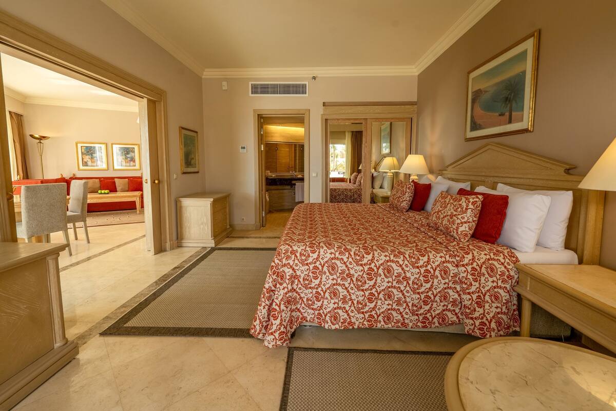 Hotelkamer met een groot bed, een bureau, een stoel, een bank en een zichtbare badkamer door een open deur.