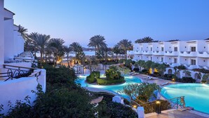 Un resort con piscina, palme e edifici bianchi.