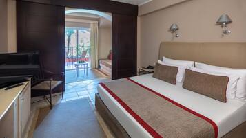 A hotel room with a bed, a desk, a chair, a television, and a balcony with a view.