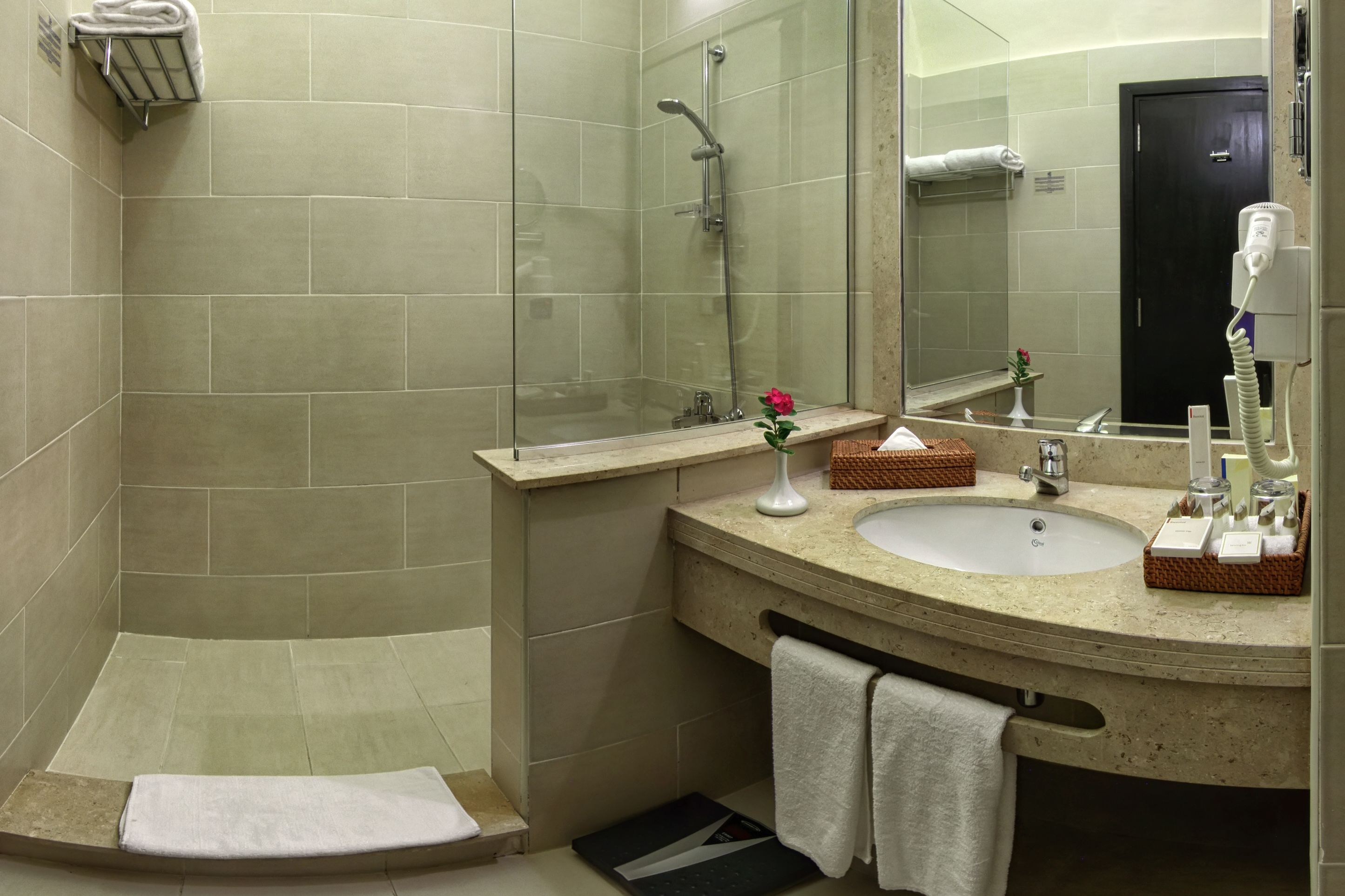 A modern bathroom with a shower, a sink, a mirror, and a towel rack.