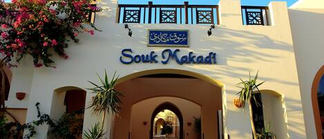 La entrada a Souk Makadi, con un arco, plantas en macetas y un cielo azul despejado.