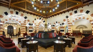 Un vestíbulo amplio con un área de estar central, techos altos de madera y un candelabro decorativo.