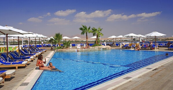 Una piscina al aire libre, sombrillas, tumbonas