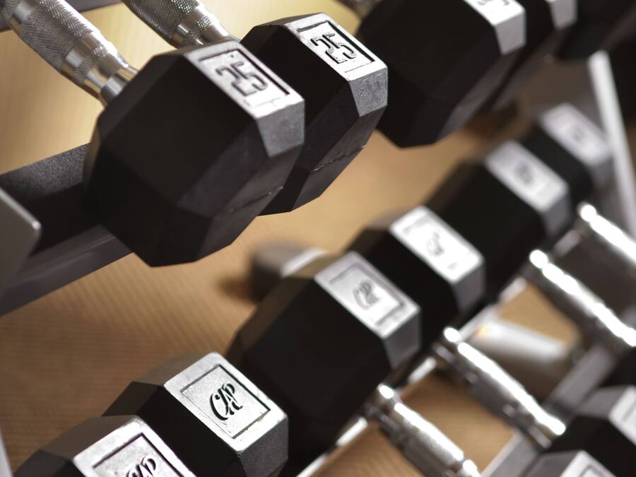 A set of black dumbbells with weight markings on a wooden surface.