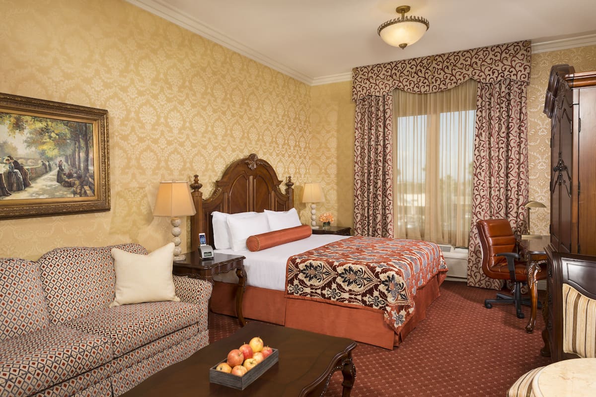Een hotelkamer met een groot bed, een bank, een bureau en een schilderij aan de muur.