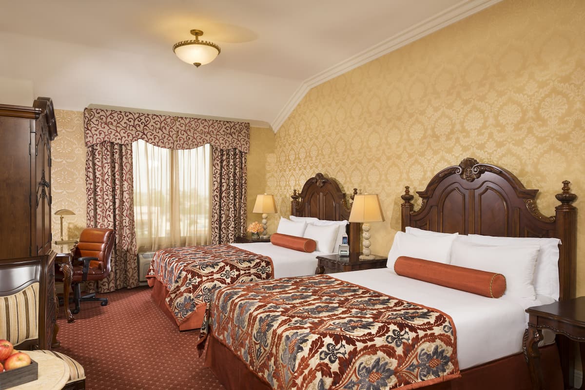 Een hotelkamer met twee bedden, een bureau, een stoel en een lamp.