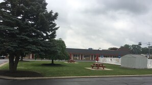 A motel with a red exterior, a picnic table, and a small shed. - Caravan Motel (Niagara Falls)