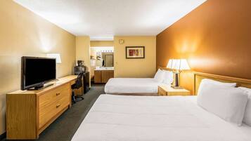 A hotel room with two beds, a TV, a desk, and a lamp.