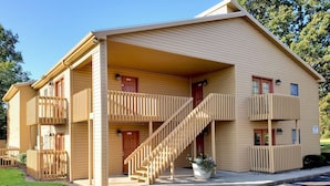 A two-story building with a covered entrance, a staircase, and a small garden area.