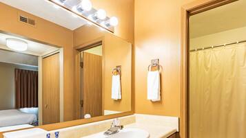 A hotel bathroom with a sink, mirror, and shower curtain.