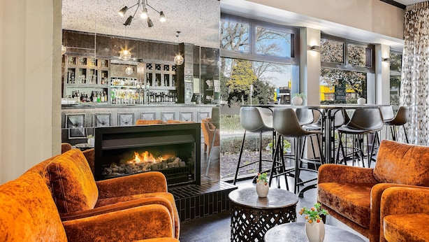 Un área de bar moderna con chimenea, asientos y vistas al exterior.