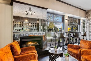 Un área de bar moderna con chimenea, asientos y vistas al exterior.