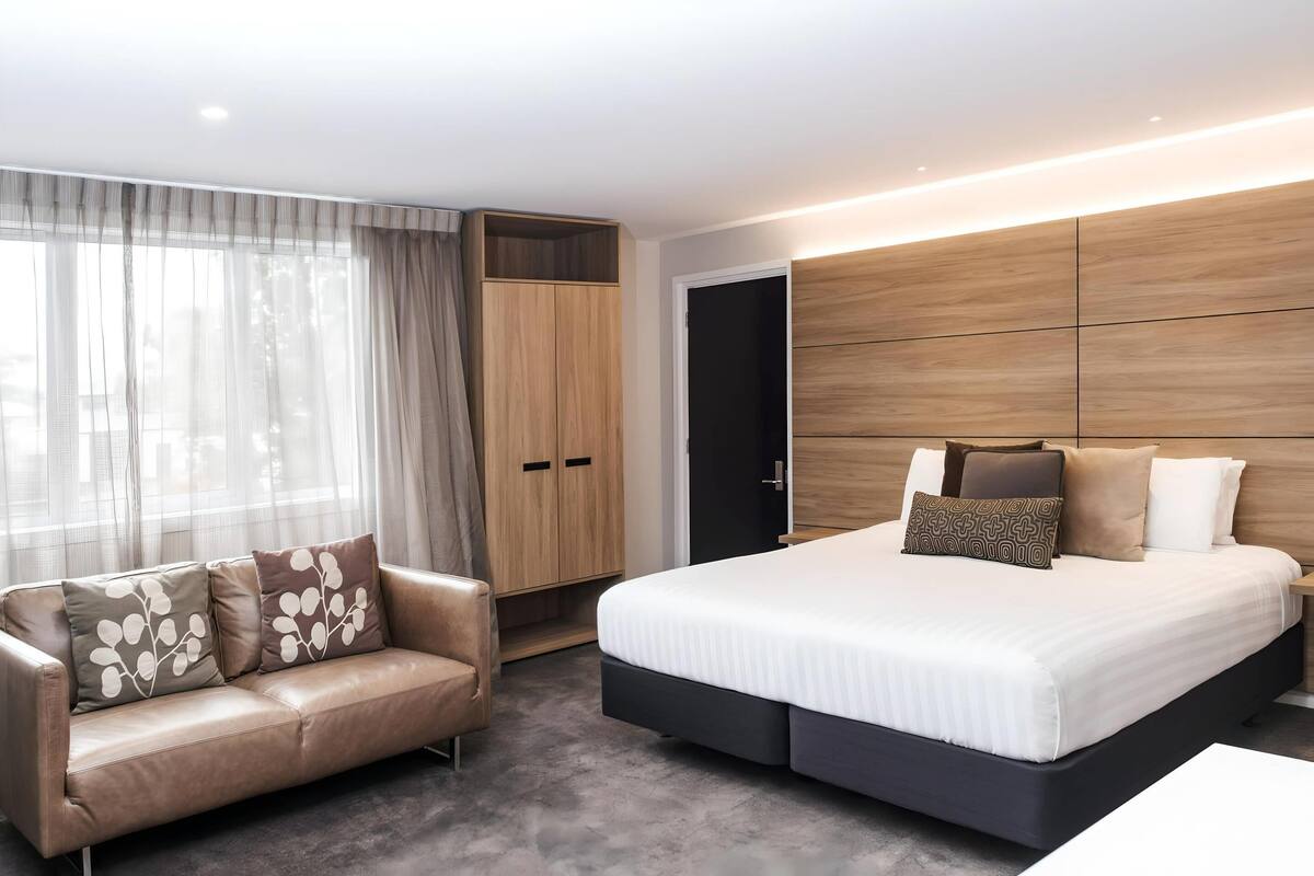 Una camera da letto moderna con un letto, una poltrona in pelle e un armadio.