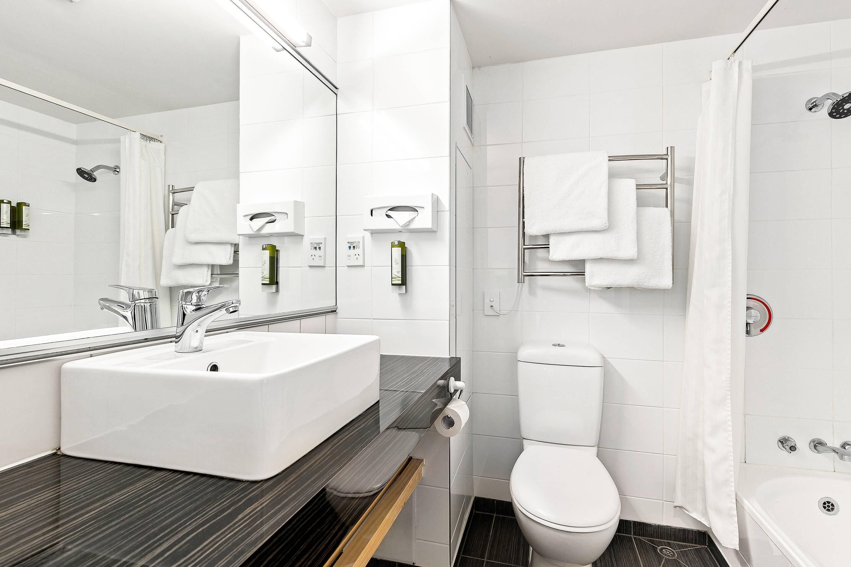 A modern bathroom with a sink, toilet, and shower.
