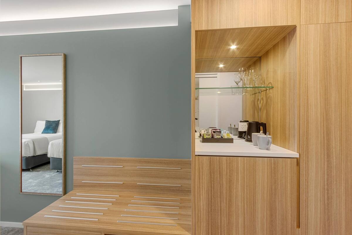 Un bagno moderno con un mobile bagno in legno, uno specchio e uno scaffale in vetro con articoli da toilette.