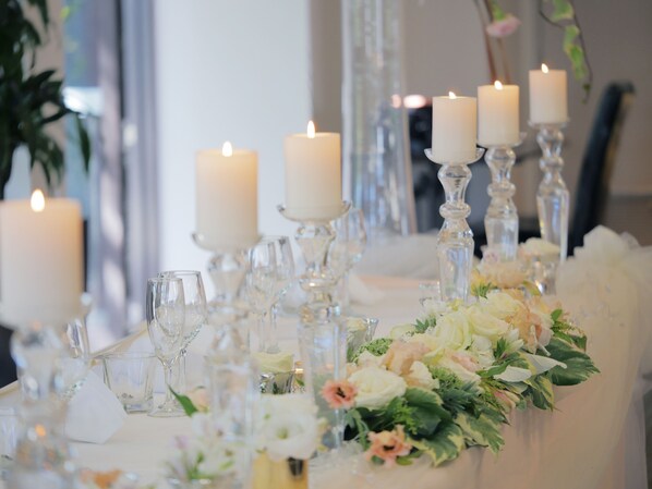 Una mesa adornada con velas, copas de vidrio transparente y arreglos florales.