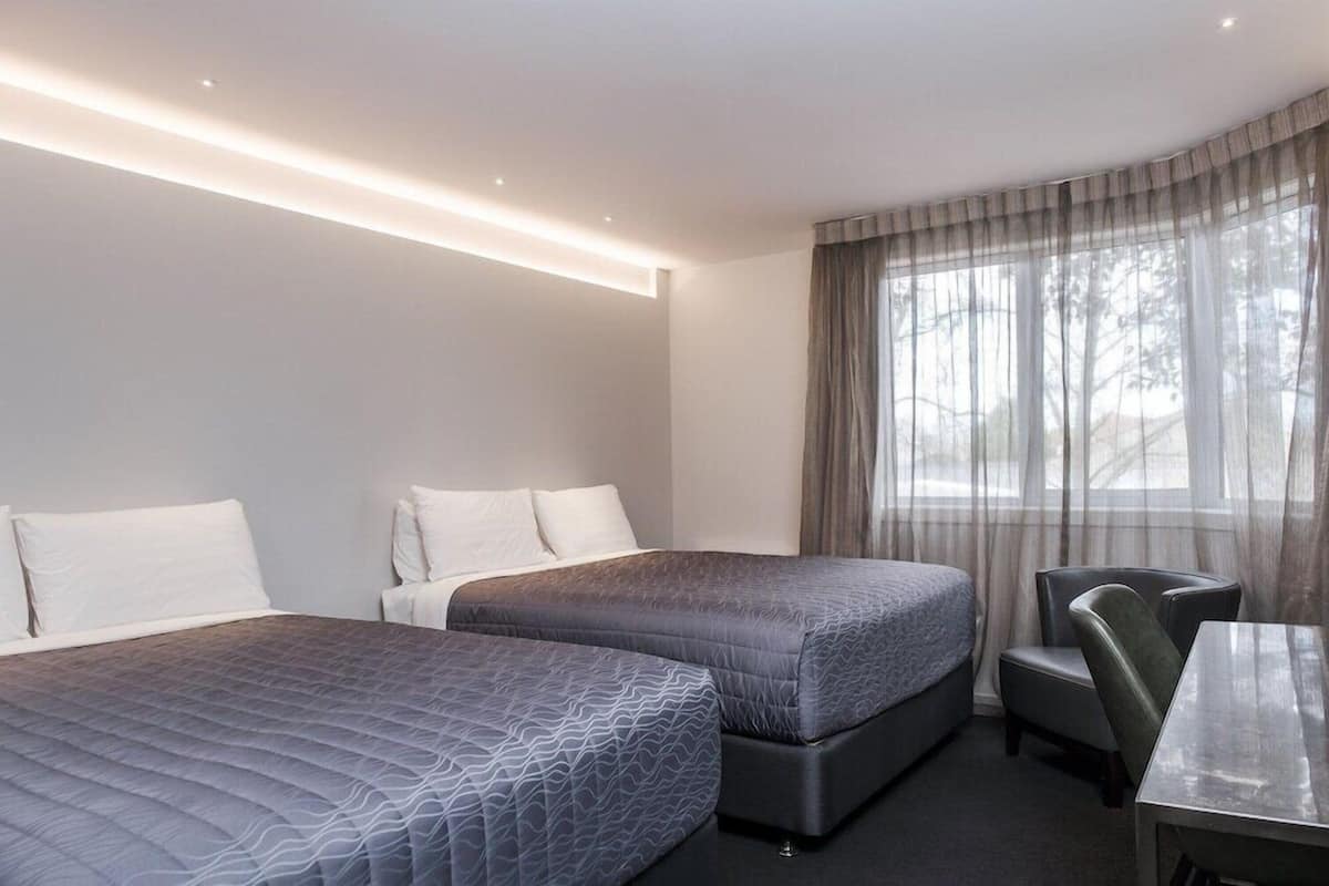 Habitación de hotel con dos camas, un escritorio y una silla.