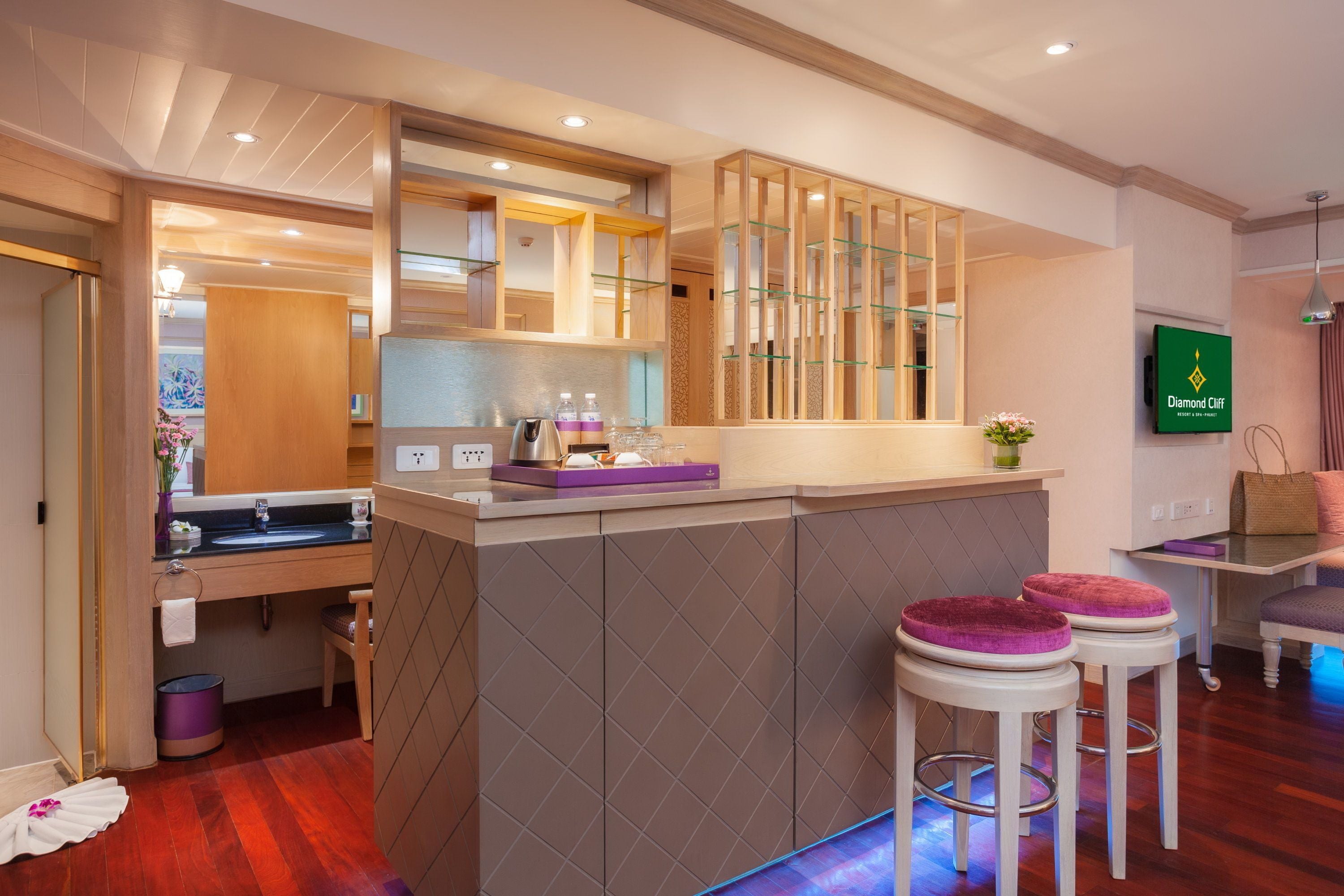 A modern kitchen with a central island, wooden cabinets, and a built-in microwave. There are two bar stools with cushioned seats.