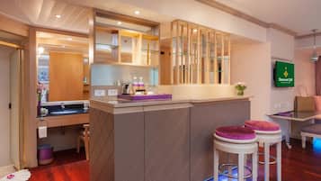 Una cocina moderna con una isla central, armarios de madera y microondas integrado. Hay dos taburetes de bar con asientos acolchados.