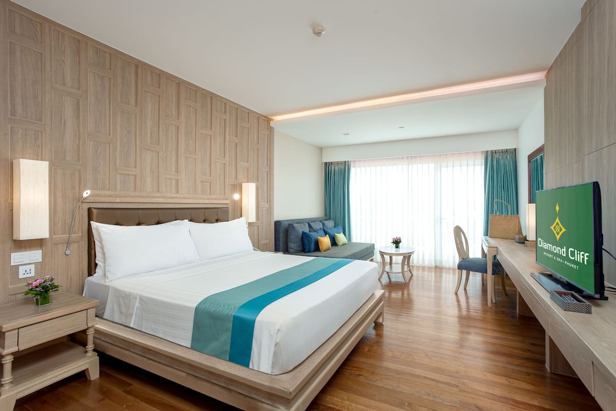 A hotel room with a large bed, a desk, a chair, and a television.