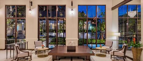 A spacious indoor area with a large wooden table, several chairs, and a view of the outdoors through large windows.