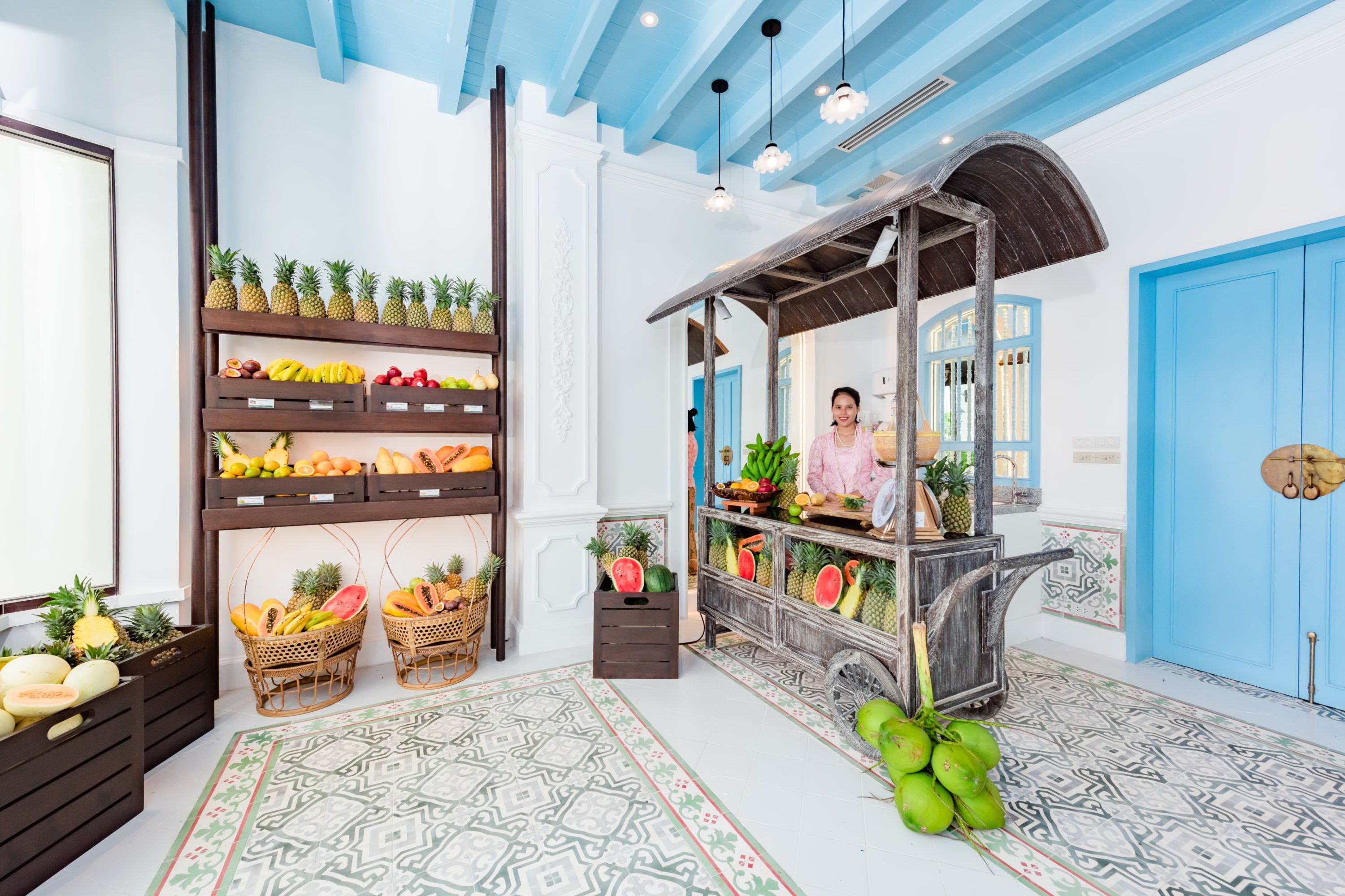 Una habitación con una presentación de frutas, un carrito de madera y un piso con diseño.