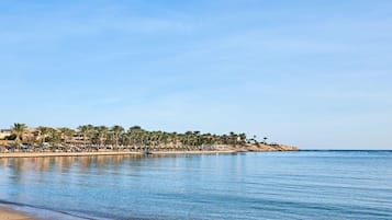 Privat strand, strandhanddukar, volleyboll och strandbarer