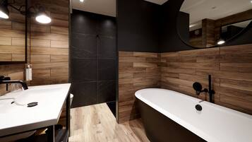 A modern bathroom with a wooden vanity, a freestanding bathtub, and a large mirror.