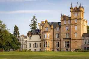 A large, historic building with multiple towers and a well-maintained lawn in front. - Cameron House on Loch Lomond (Alexandria)
