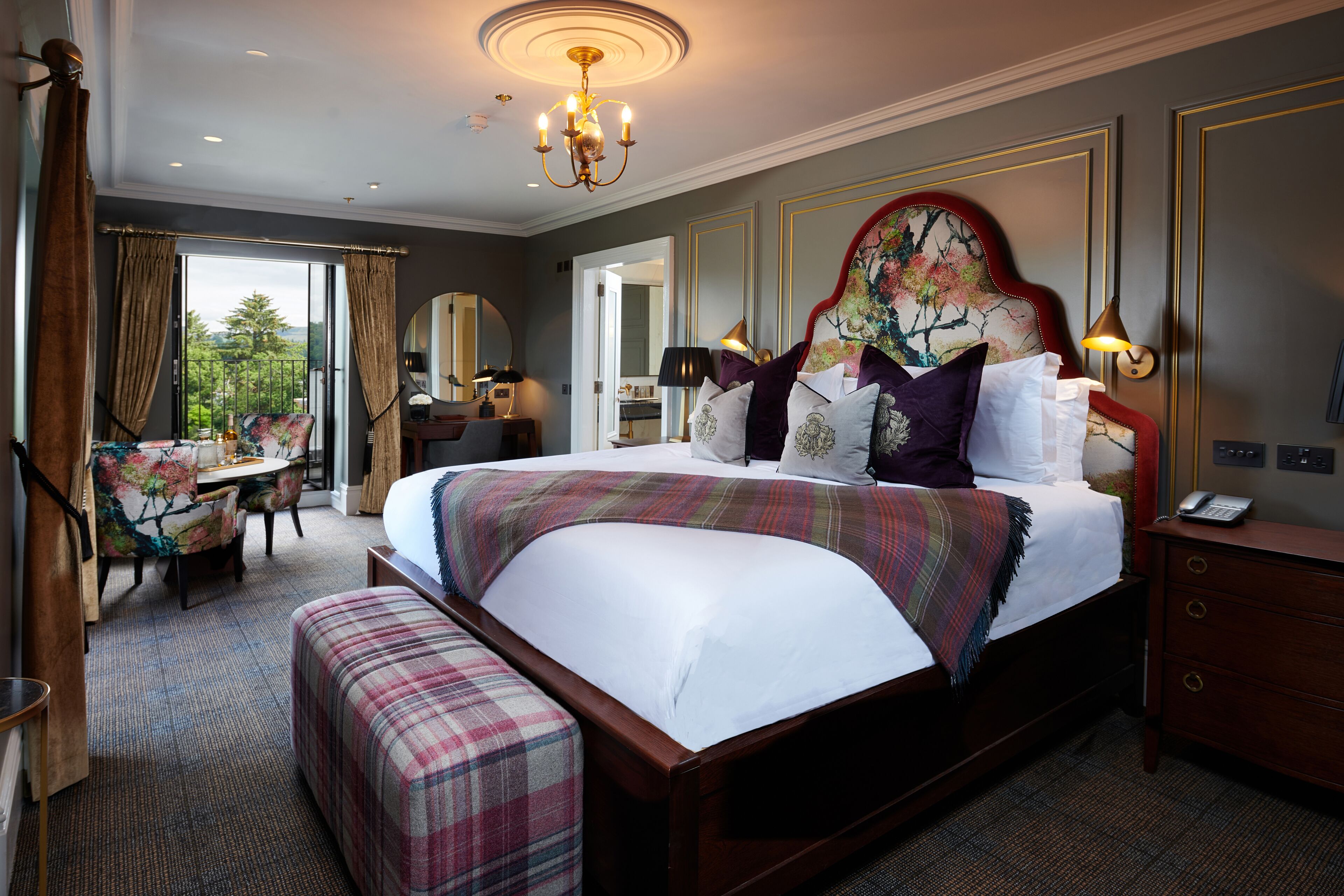 A hotel room with a large bed, a desk, a chair, and a view of the outdoors.