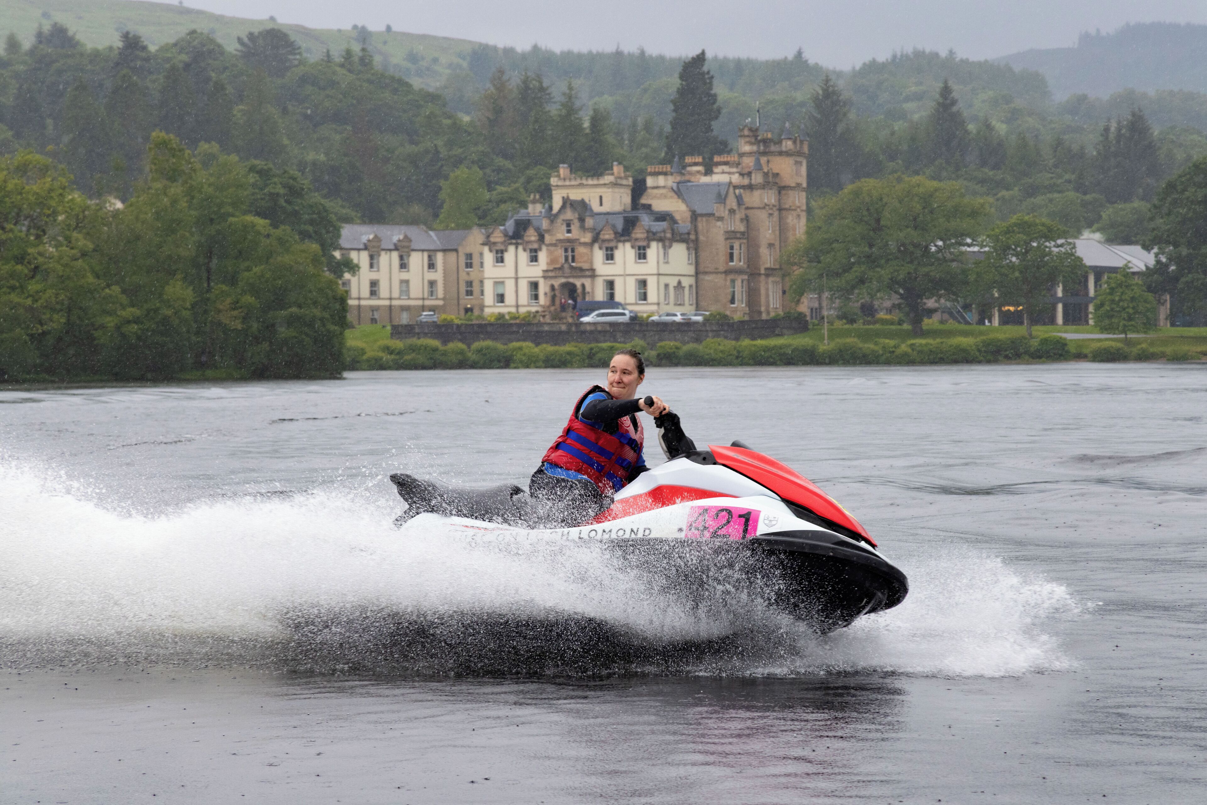 Una persona en un jet ski con el número 421, rodeada de agua salpicando.