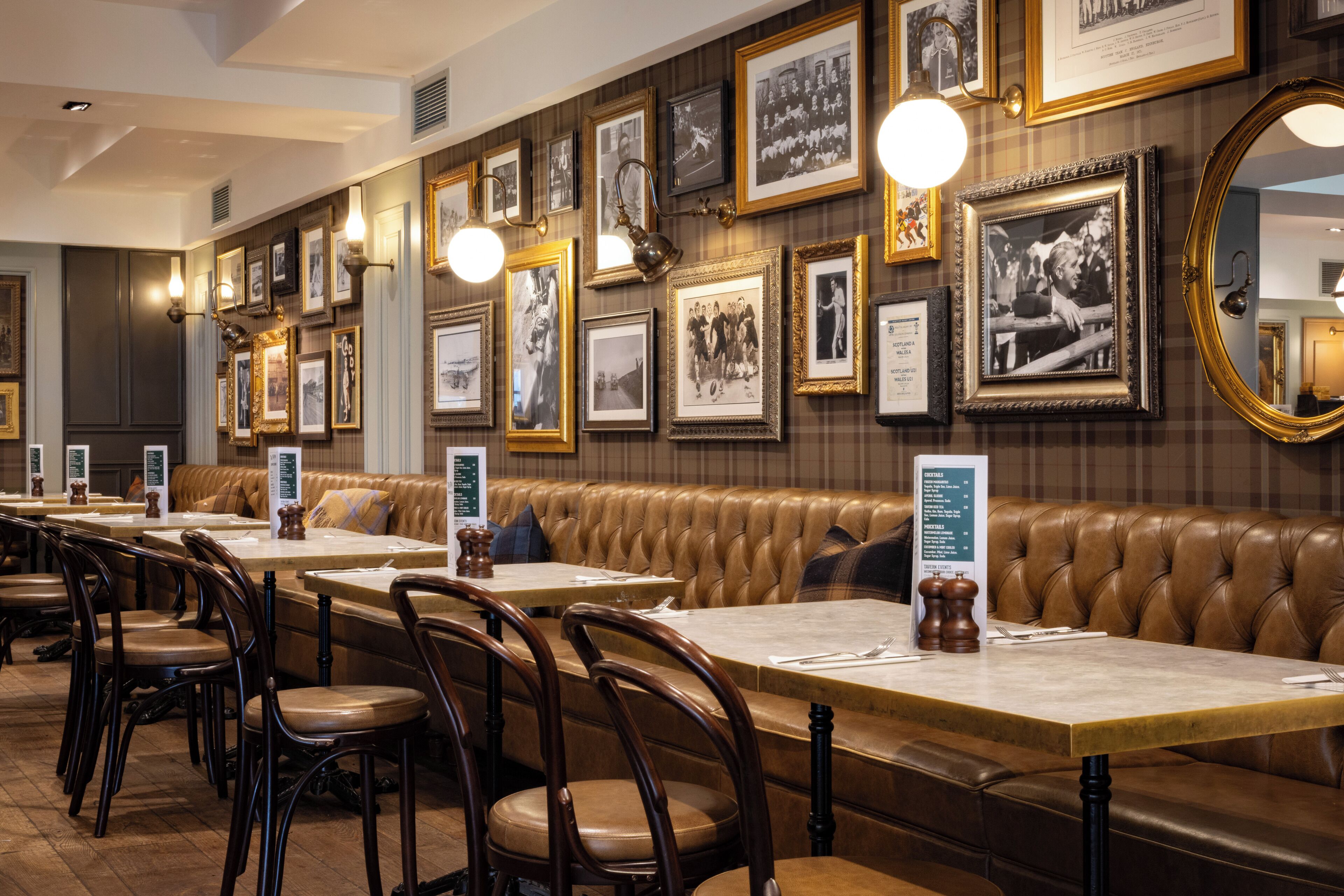 A restaurant with leather booths, wooden tables, and framed photographs on the walls.
