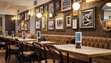 A restaurant with leather booths, wooden tables, and framed photographs on the walls.
