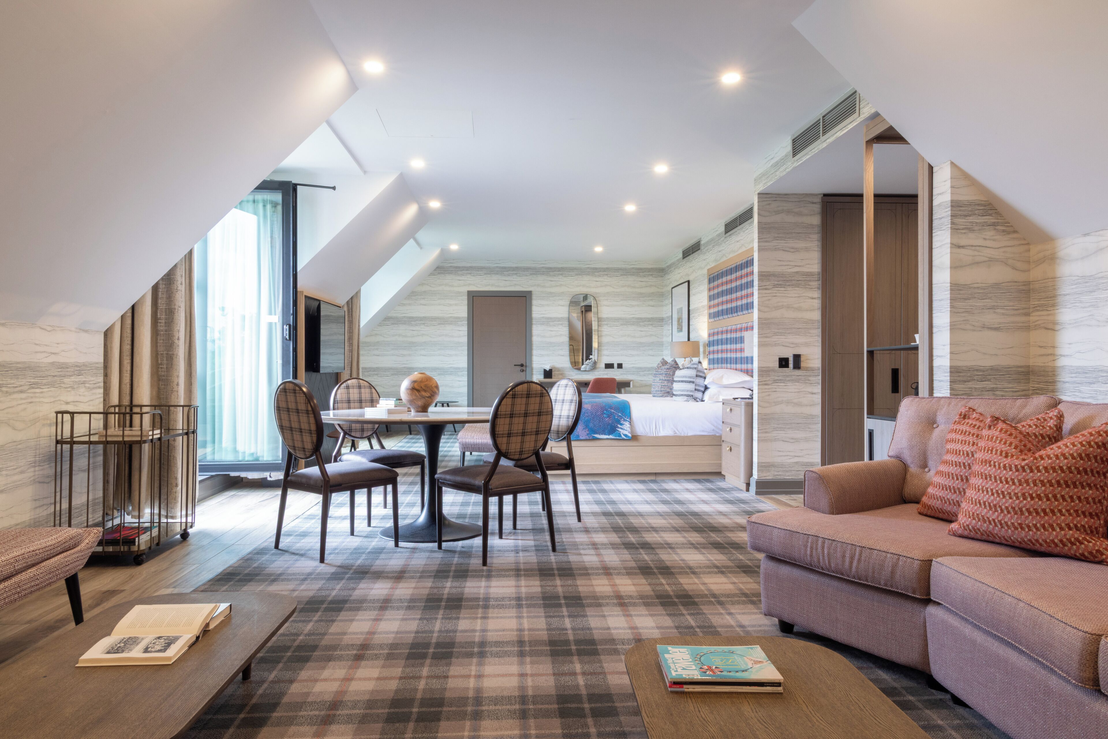 Un interior moderno con comedor, sofá y una habitación visible a través de una puerta abierta.