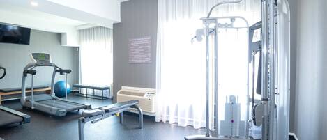 A fitness center with treadmills, a stationary bike, a rowing machine, and a weight bench.