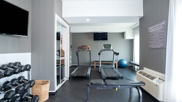A fitness center with treadmills, a stationary bike, and dumbbells.