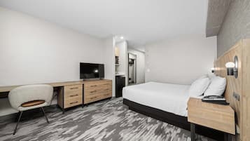 A modern hotel room with a bed, desk, chair, and a television.