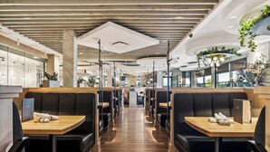 Un restaurant moderne avec des banquettes, des tables en bois et une allée centrale.